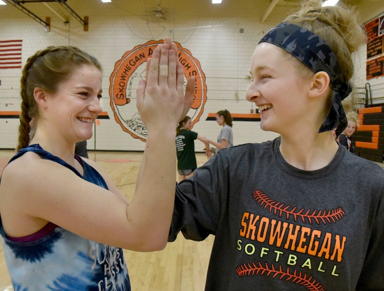 Skowhegan pitcher Sydney Ames, left, and catcher Sydney Reed share a laugh in the school's gymnasium during a preseason practice.