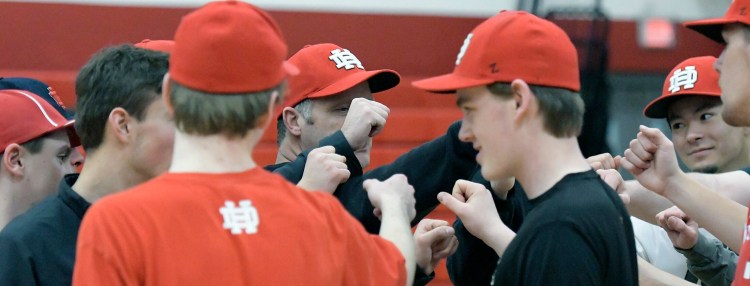 Hall-Dale High School pitchers and catchers knock knuckles during a preseason practice in Farmingdale..