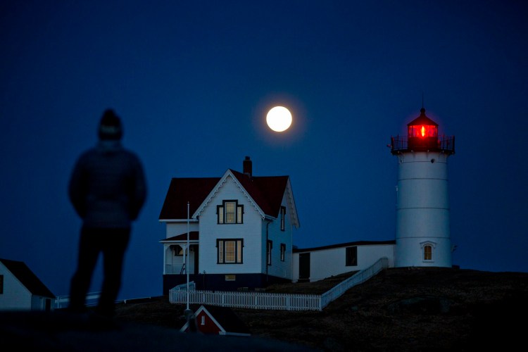 Michael Cabelin of York watches a full moon rising over Nubble Light on March 20.
