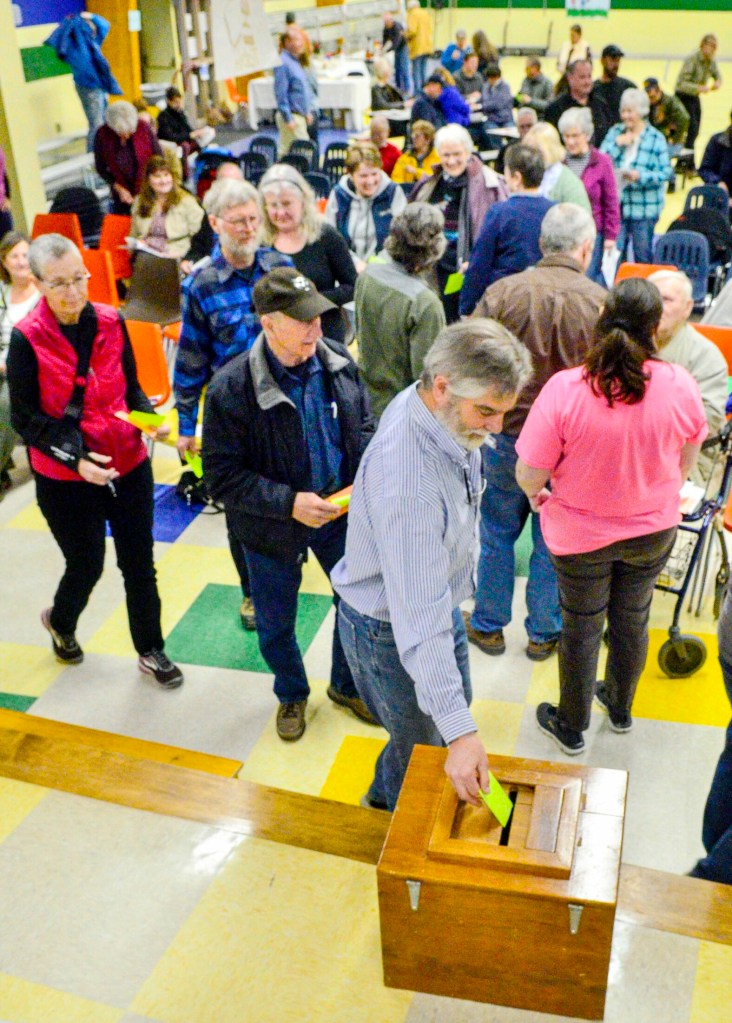 Residents vote by secret ballot Saturday on an article about borrowing money to buy a used front end loader during Town Meeting at James H. Bean School in Sidney. The measure failed by one vote.