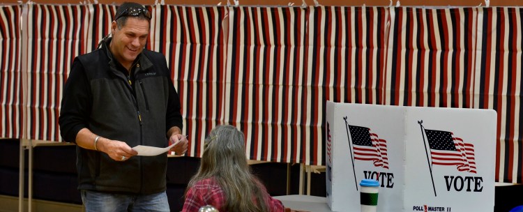 Norridgewock resident and state lawmaker Brad Farrin speaks with election clerk Helen Balgooyen before casting his ballot during elections at the Mill Stream Elementary School in Norridgewock in March 2018. A Norridgewock group is working to get enough signatures on a petition to put before voters in March a question that would change an alcohol-related blue law the town currently follows.