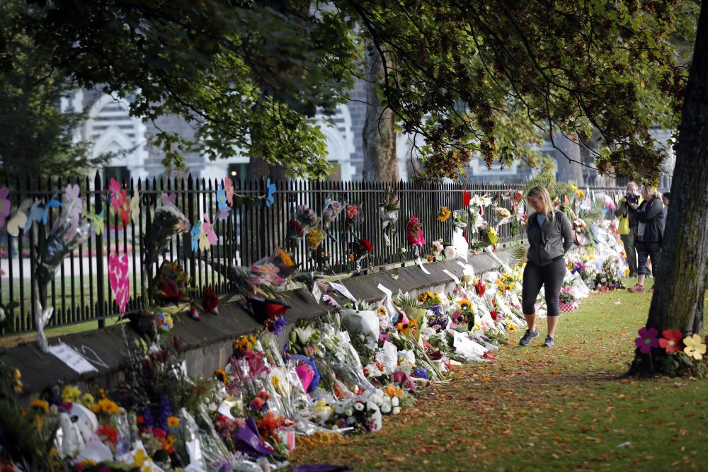 Mourners paying their respects at a makeshift memorial at the Botanical Gardens in Christchurch, New Zealand, Saturday, March 16, 2019. New Zealand's stricken residents reached out to Muslims in their neighborhoods and around the country on Saturday, in a fierce determination to show kindness to a community in pain as a 28-year-old white supremacist stood silently before a judge, accused in mass shootings at two mosques that left dozens of people dead. (AP Photo/Vincent Thian)