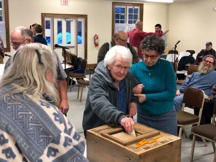 Shari Lily, left, watches as Eleanor Everson casts a ballot at Monday's special town meeting in Dresden. 