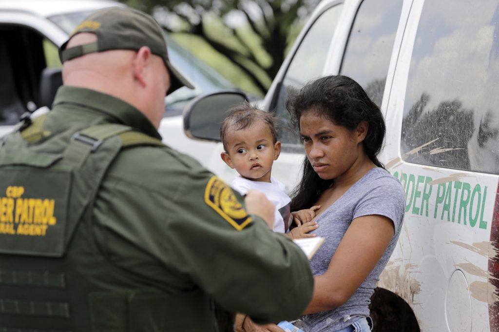 A mother migrating from Honduras holds her 1-year-old child as she surrenders to Border Patrol agents after illegally crossing into the U.S. on Monday near McAllen, Texas. Confusion rose Monday over the Trump administration's "zero-tolerance" policy.