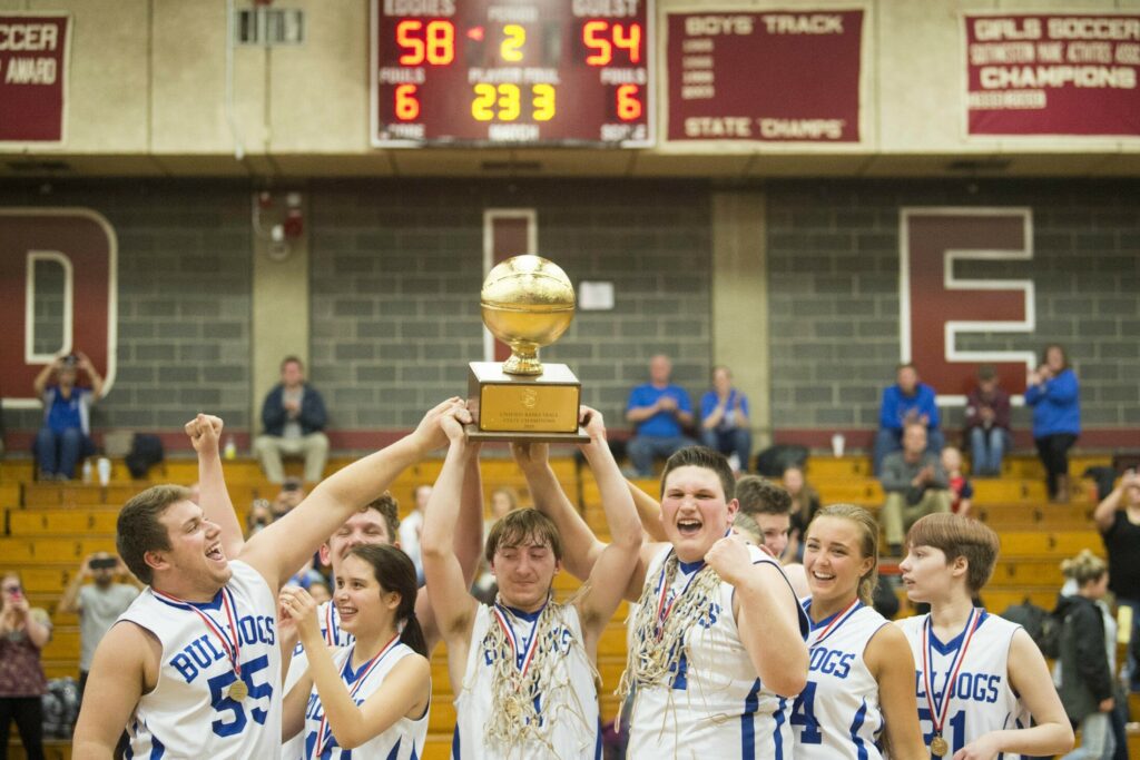 Madison Area Memorial High School's Scott Sawtelle (1) hoists the gold ball over his head with his teammates after defeating Westbrook High School in the Unified Championship game at Edward Little High School in Auburn on Tuesday.