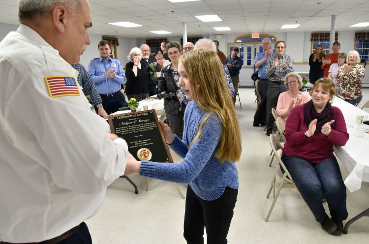 China Village Fire Chief Tim Theriault presents a lifesaving award plaque to Aislynn Savage, 12, on Tuesday during the annual Fire Department meeting in China. Aislynn's mother Laura, right, and firefighters and family applaud. Aislynn was recognized for her actions on Feb. 23 when her mother experienced a medical incident while driving. Aislynn took the wheel and guided the car safely into a snowbank and avoided hitting trees or vehicles. 