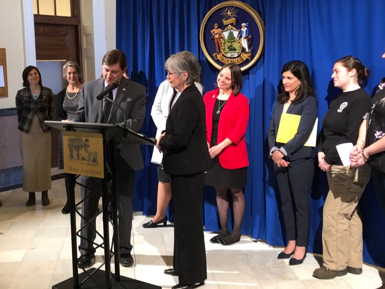 Sen. Cathy Breen of Falmouth, at center, looks on as Senate President Troy Jackson of Allagash signs her bill to reduce the gender pay gap by prohibiting employers from asking about a candidate’s compensation history before a job offer. 
