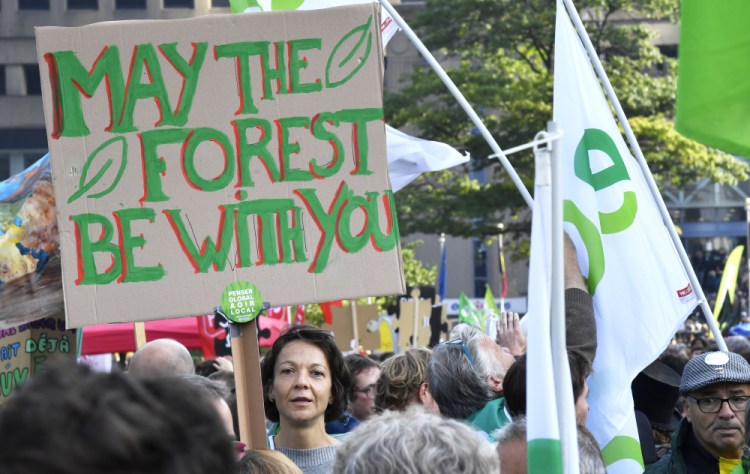 A protester holds up a sign during a climate march in Brussels on Sunday. Some 80 organizations are joining in a climate march through Brussels to demand change and push politicians to effective action in Glasgow later this month.