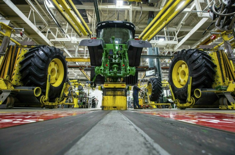 Wheels are attached as workers assemble a tractor at John Deere's Waterloo, Iowa, assembly plant in April 2019.