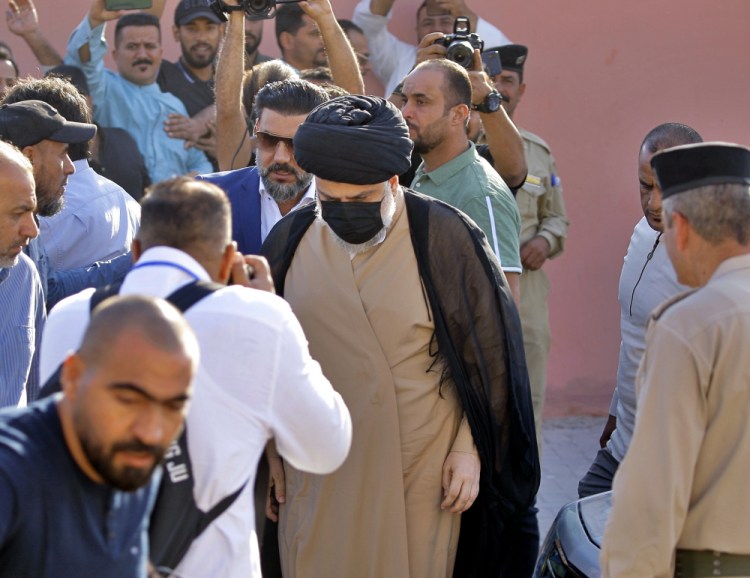 Populist Shiite cleric Muqtada al-Sadr, center, arrives at a polling center to vote in Najaf, Iraq, on Sunday. Iraq closed its airspace and land border crossings as voters headed to the polls to elect a parliament that many hope will deliver much needed reforms after decades of conflict and mismanagement. 
