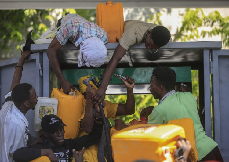 People wrangle over a gas pump as they try to get their tanks filled at a gas station, in Port-au-Prince, Haiti, Thursday. Nov 4. 