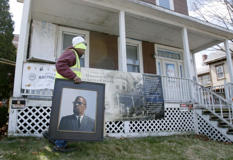 Rodnell P. Collins carries a painting of his uncle, Malcolm X, outside the house where the slain African-American activist spent part of his teen years in the Roxbury neighborhood of Boston., in this March 2016 photo. 