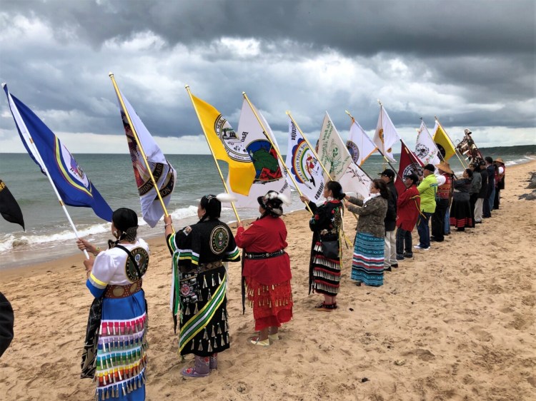 Native women veterans in flag ceremony when tobacco was sprinkled on the sea surf on Omaha Beach. (Photo by Harald Prins)