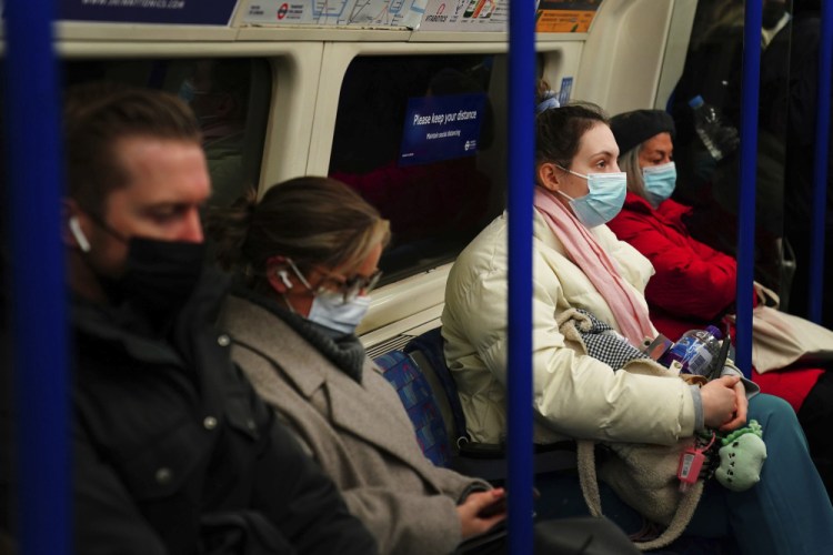 Commuters in a London underground tube train wear face masks to curb the spread of COVID-19, now mandatory on public transport in Britain after the emergence of new Omicron variant, in London, Tuesday, Nov. 30, 2021. 