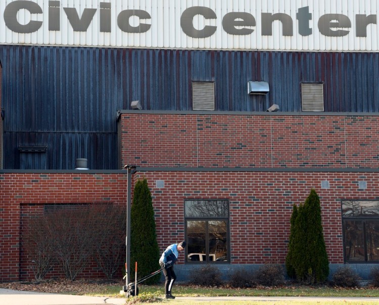 A woman walks a dog Nov. 30 outside the Augusta Civic Center. Though the center was beginning to rebound earlier last summer from a slew of 2020 cancellations, a surge in COVID-19 cases driven by the delta variant prompted most bookings for September and October to cancel, leaving the venue operating at a loss. New federal rules will now allow city officials to use some pandemic relief funds to offset losses at the facility.
