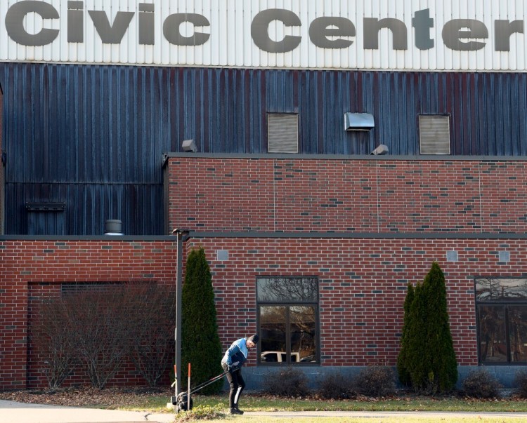 A woman walks a dog Nov. 30 outside the Augusta Civic Center. Though the center was beginning to rebound earlier last summer from a slew of 2020 cancellations, a surge in COVID-19 cases driven by the delta variant prompted most bookings for September and October to cancel, leaving the venue operating at a loss. New federal rules will now allow city officials to use some pandemic relief funds to offset losses at the facility.