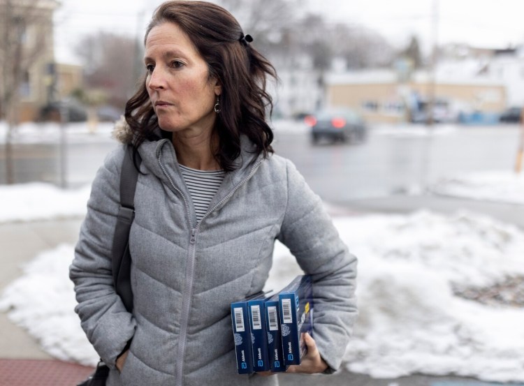 Ann-Marie Bouchard holds at-home COVID-19 tests that she bought at Walgreens on Forest Avenue on Thursday. She and her husband bought six tests total, some to give away and others for their family to use before upcoming travel or in case of exposure.