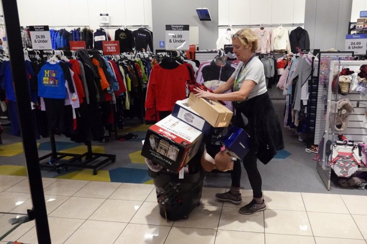 A shopper pushes her cart full of items down an isle during a Black Friday sale at Macy's in Indianapolis.