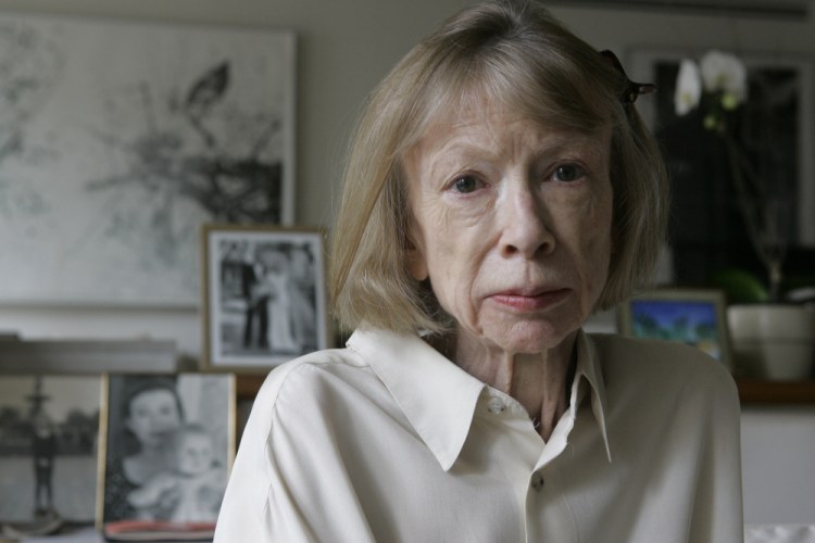 Author Joan Didion sits in front of a photo of herself holding her daughter, Quintana Roo, and another picture of her daughter's wedding, in her New York apartment Sept. 26, 2005. 