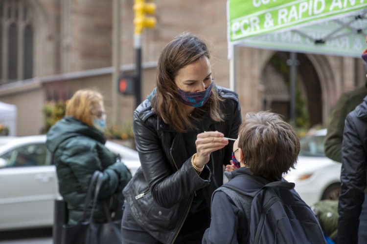Katie Lucey administers a COVID-19 test on her son Maguire at a PCR and Rapid Antigen COVID-19 coronavirus test pop up on Wall Street in New York on Thursday, Dec. 16. 
