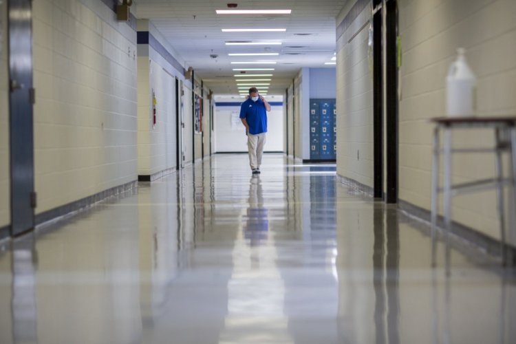 A middle school principal walks the empty halls of his school as he speaks with one of his teachers to get an update on her COVID-19 symptoms, in August in Wrightsville, Ga. On Monday, U.S. health officials cut isolation restrictions for Americans who catch the coronavirus, from 10 to five days, and also shortened the time that close contacts need to quarantine. 