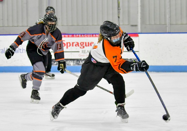 Brunswick's Lily Hattrick, left, watches as Kaylyn Bourque shoots and score her first goal during a hockey game Nov. 27, 2021, at The Camden National Bank Ice Vault in Hallowell. Bourque played for the team representing Winslow, Gardiner, Brewer, Messalonskee, Lawrence and Erskine Academy. 