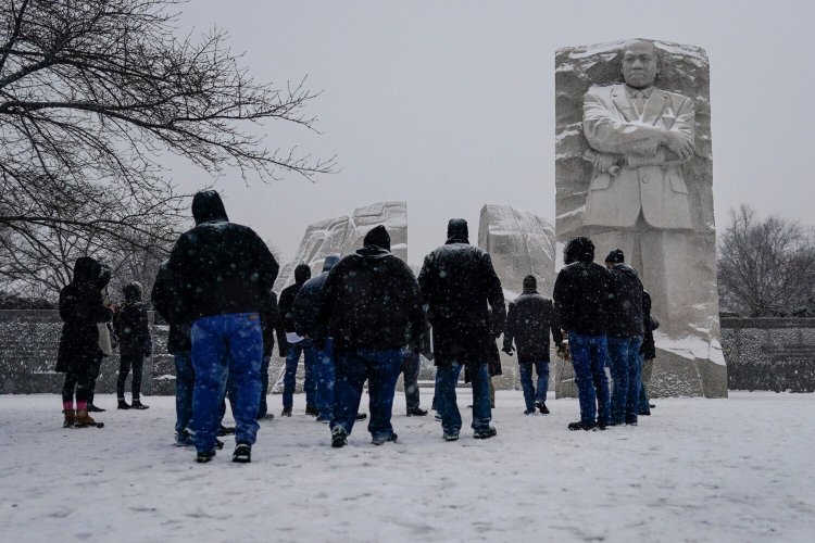 Visitors look to the Martin Luther King, Jr. Memorial as snow falls in Washington on Sunday. Ceremonies scheduled for the site on Monday, to mark the Martin Luther King Jr. national holiday, were canceled because of the weather. 