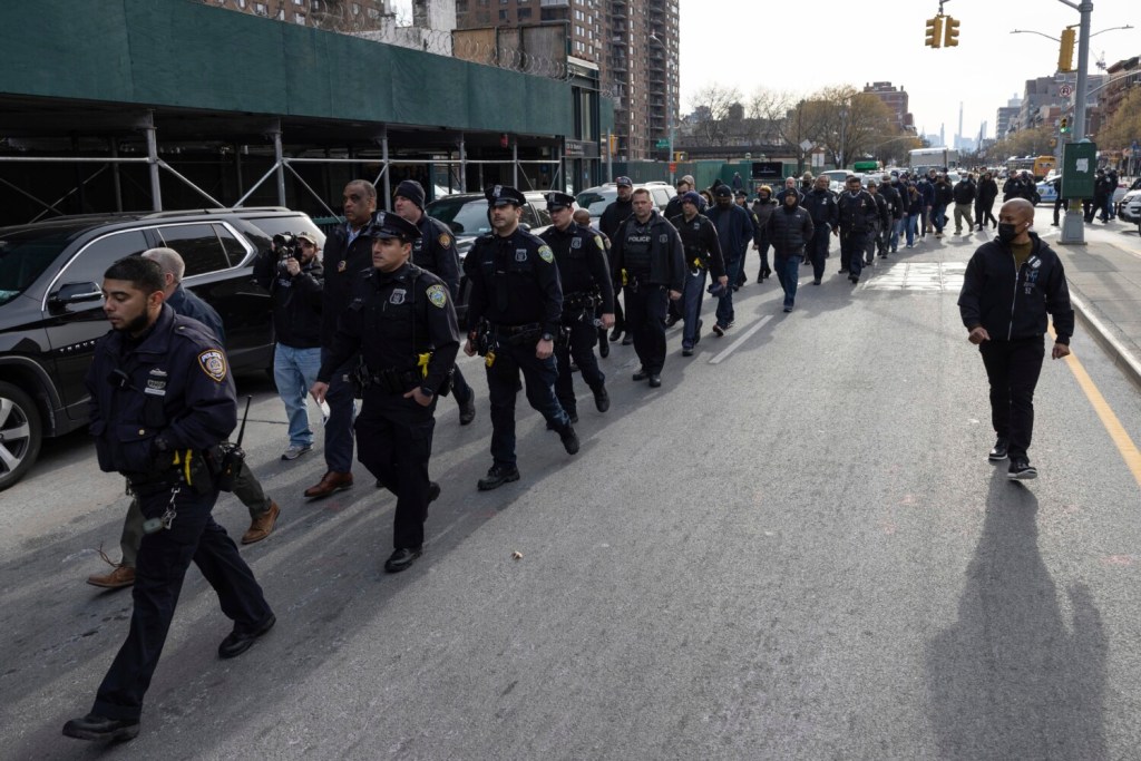 Police officers from New York and Westchester march from the NYPD 32nd precinct to Harlem Hospital near the scene of a shooting in the Harlem neighborhood of New York, Sunday, Jan. 23, 2022. (AP Photo/Yuki Iwamura)
