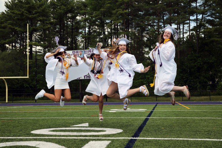 Deering High School graduates Andrea Garcia, left, valedictorian Linh Nguyen, Lauren Tosi and Stephanie MacVane jump for joy for photographers after graduation.