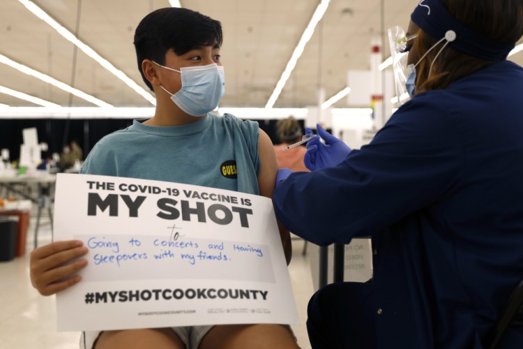 Lucas Kittikamron-Mora, 13, holds a sign in support of COVID-19 vaccinations as he receives his first Pfizer vaccination at the Cook County Public Health Department, May 13, 2021 in Des Plaines, Ill. 