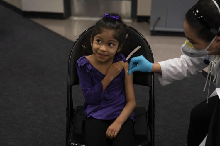 Elsa Estrada, 6, smiles at her mother as pharmacist Sylvia Uong applies an alcohol swab to her arm before administering the Pfizer COVID-19 vaccine at a pediatric vaccine clinic for children ages 5 to 11 set up at Willard Intermediate School in Santa Ana, Calif., in November. As of Tuesday,  just over 17 percent of children in the U.S. ages 5 to 11 were fully vaccinated, more than two months after shots for them became available. 