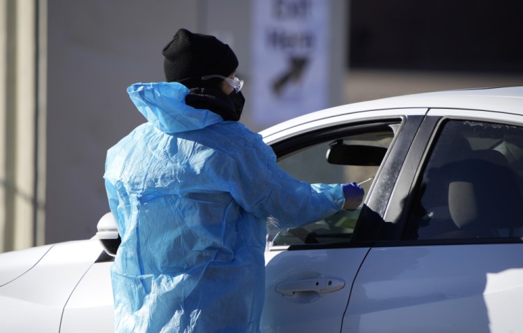 A medical technician performs a nasal swab test on a motorist queued up in a line at a COVID-19 testing site near All City Stadium Dec. 30 in southeast Denver.