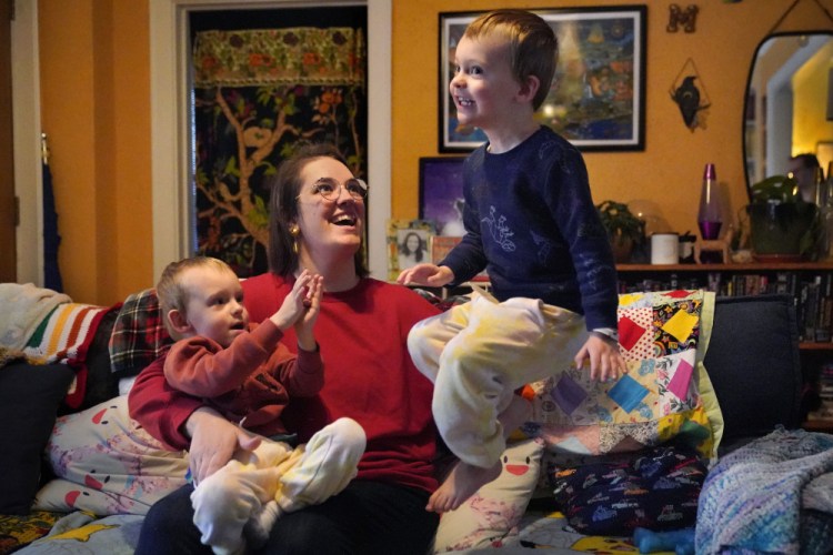 Heather Cimellaro holds her 3-year-old son, Charlie, while his twin brother, Milo, jumps on a couch Wednesday at their home in Auburn. Heather Cimellaro is one of many parents concerned about the omicron surge and the dilemma it's posing for families of children too young to be vaccinated. 