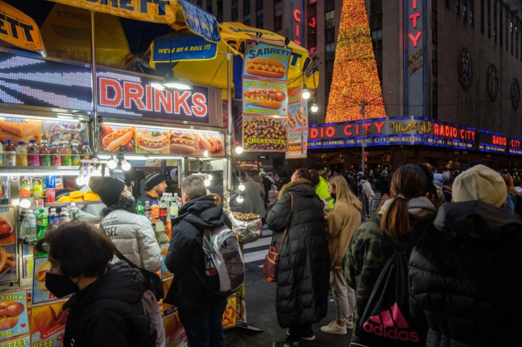 Tourists wait in line to purchase food from a street vendor in New York on Dec. 4, 2021. MUST CREDIT: Bloomberg photo by Christopher Occhicone.