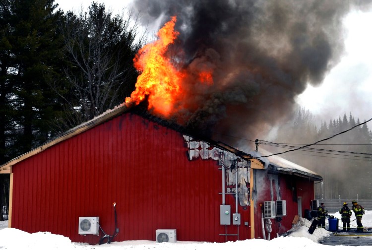 Flames roar through the roof of a building Monday at 647 Webber Pond Road in Vassalboro. Formally the location of a paintball business, the structure, described as a complete loss, was being used to cultivate marijuana.