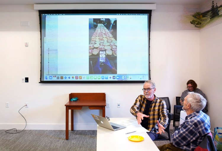 During a talk in April at the Falmouth Memorial Library , Falmouth resident John Messer talks about his experience volunteering with the World Central Kitchen in Poland, making food for Ukranian refugees. Here, he shows a photo while explaining how a team of volunteers mass-produced sandwiches. "No matter where you go in the world, everybody loves a sandwich," he said.