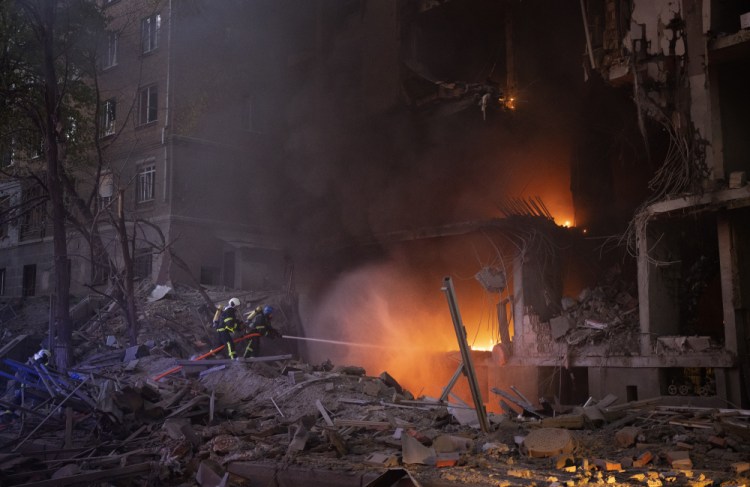 Firefighters try to put out a fire following an explosion Thursday in Kyiv, Ukraine. Russia mounted attacks across a wide area of Ukraine on Thursday, bombarding Kyiv during a visit by the head of the United Nations.
