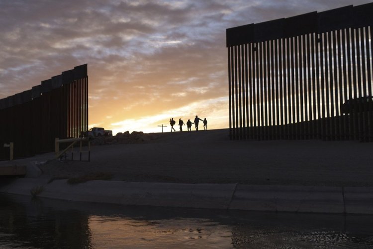 Two migrant families from Brazil pass  through a gap in the border wall to reach the United States after crossing from Mexico in Yuma, Ariz., to seek asylum on June 10. 