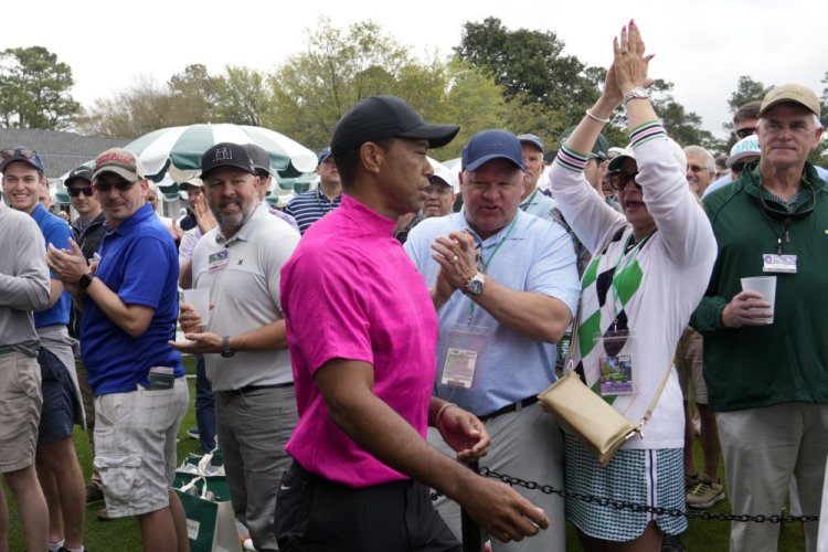 Spectators cheer as Tiger Woods heads to the first tee during the first round at the Masters golf tournament on Thursday morning.