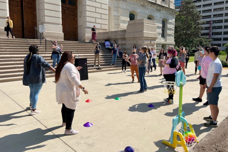 Activists rally against a bill that bans transgender girls from competing in girls sports by playing sidewalk games outside of the Indiana Statehouse on Tuesday in Indianapolis. Cara Nimskey said her daughter "dreams of playing basketball in high school. It's unfair exclusion – she'll be crushed if this goes through.”
