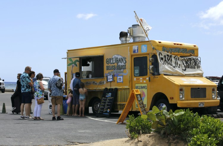 People line up at a food truck parked near Waikiki Beach on Monday in Honolulu. In Hawaii, which once had one of the nation's lowest rates of infection, hospitalization and death, new cases are surging but tourists have been flocking to its beaches.