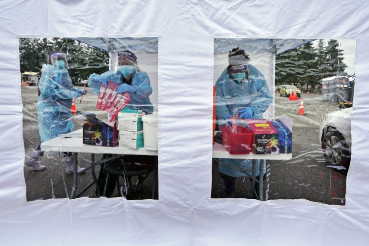 Workers at a drive-up COVID-19 testing clinic prepare PCR tests on Jan. 4 in Puyallup, Wash. 