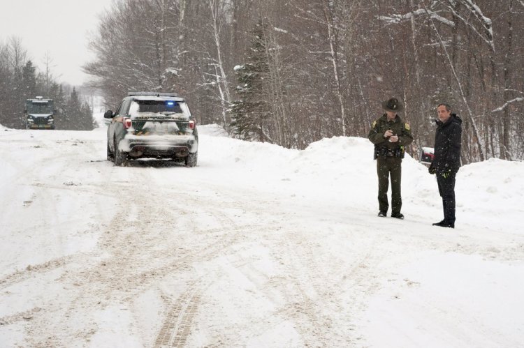A Vermont State Trooper, center, speaks to a homeowner on Thursday,  Jan. 8, 2018 near an area on Peacham Road, in Barnet, Vt., where the body of Gregory Davis was found. Federal prosecutors say a conspiracy that resulted in the murder of Gregory Davis grew out of a financial dispute between him and one of the men now charged with arranging to have him killed.