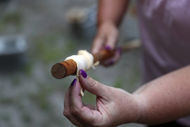 TOPSHAM, ME - JULY 19: Elaine Taylor, a staff member of Girl Scouts of Maine, wraps crescent roll dough around a wooden dowel to cook a dough boy over a campfire. (Staff photo by Ben McCanna/Staff Photographer)