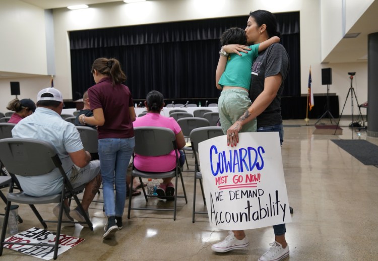Rachel Martinez carries her son and a protest sign as she attends a city council meeting, on July 12 in Uvalde, Texas. 