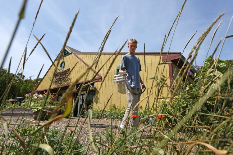 Aidan Connor, an employee at Jordan Farm in Cape Elizabeth, waters plants outside the farm market on Sunday. Watering is essential, as much of coastal Maine has moved into severe drought status.