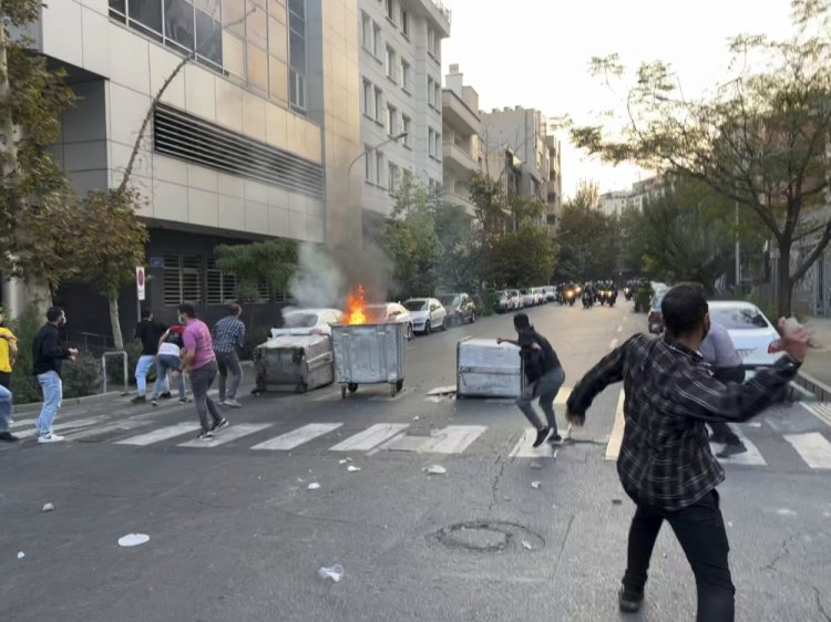 Protesters throw stones at anti-riot police during a demonstration over the death of 22-year-old Mahsa Amini, who had been detained for violating the country's dress code, on Tuesday in downtown Tehran, Iran. 