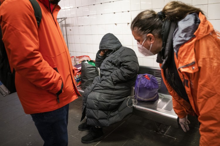 Homeless outreach personnel talk to a person sleeping on a bench in the Manhattan subway system in New York City. The Coalition for the Homeless  denounced Mayor Eric Adams' plan, saying the city should focus on expanding access to voluntary psychiatric treatment.