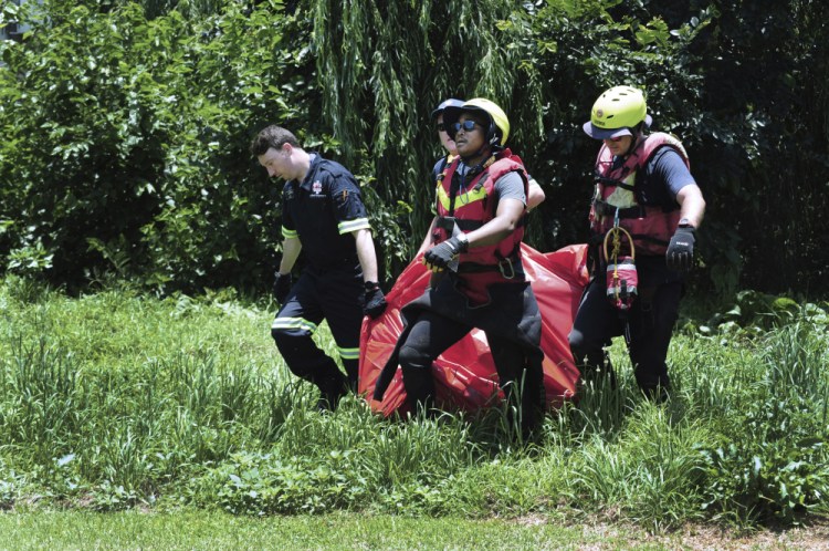 Rescuers carry the body of a flash flood victim that was retrieved from the Jukskei river in Johannesburg on Sunday.(AP Photo)