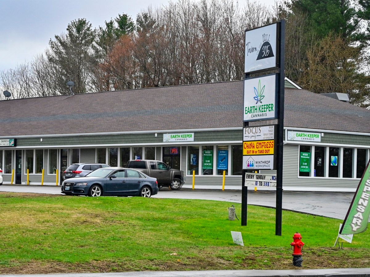 Exterior view of strip mall behind tall sign listing business names